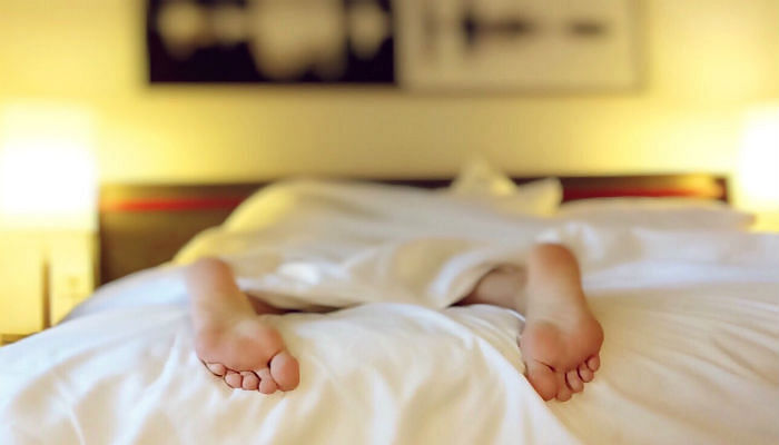 person sleeping on bed with legs sticking out