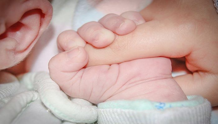 baby's hand clutching onto an adult finger.