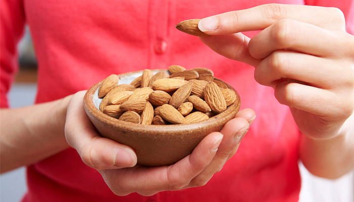 woman eating healthy snack of almond nuts