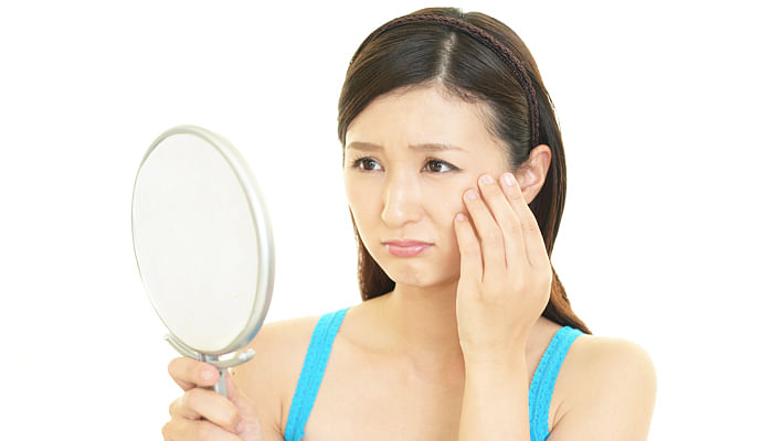 woman-looking-at-mirror-unhappy-with-skin